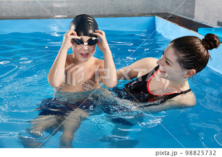 Boy learning to swim and dive in pool with teacher Boy learning to swim and dive in pool with teacher 98825732