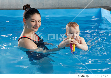 Little baby learning to swim in pool with teacher Little baby learning to swim in pool with teacher 98825752