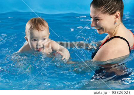 Little baby learning to swim in pool with teacher Little baby learning to swim in pool with teacher 98826023