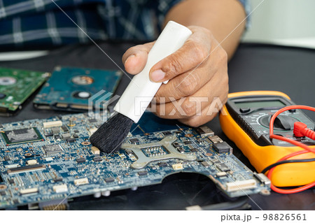 Technician use brush and air blower ball to clean dust in circuit board computer. Repair upgrade and maintenance technology. 98826561
