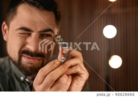 Jeweler working with gemstone on blurred background Jeweler working with gemstone on blurred background 98826668