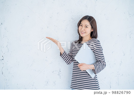 パソコンを持ってサービスを案内をする女性 98826790