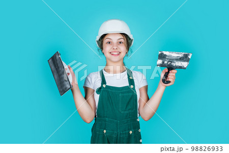 This is my place. kid wear helmet on construction site. teen girl plasterer with tool spatula. child on repairing work. concept of renovation in workshop. busy professional carpenter with trowel 98826933
