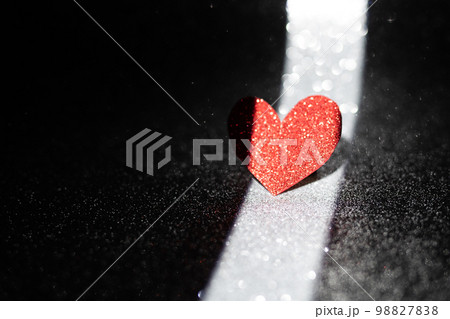 Red heart on a dark background with a narrow band of light. Romantic postcard. Valentine's Day is the feast of lovers. 98827838