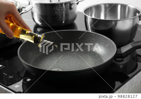 Woman pouring cooking oil from bottle into frying pan, closeup 98828127