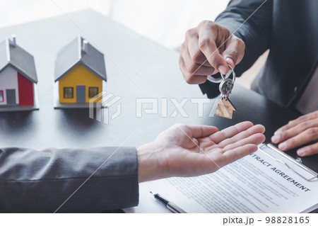 Home sales,home rental and real estate concept.Hands of estate agent giving keys to the Customer after sign the document while explain about the terms of the home purchase or rental agreement 98828165