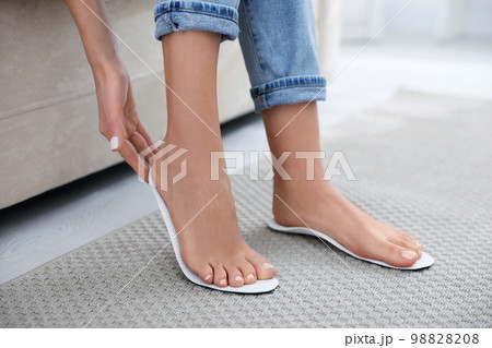 Woman fitting orthopedic insole at home, closeup 98828208
