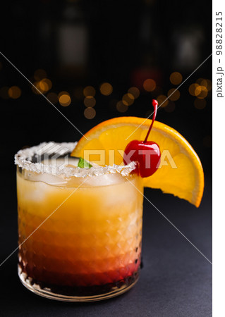 Fresh alcoholic Tequila Sunrise cocktail on black table 98828215