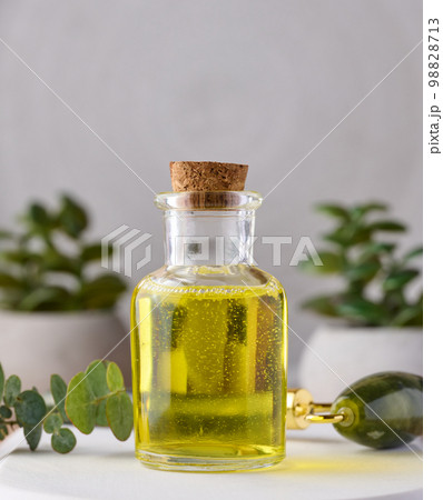 Transparent glass bottle with yellow oil and eucalyptus branch, cosmetic product Transparent glass bottle with yellow oil and eucalyptus branch, cosmetic product 98828713