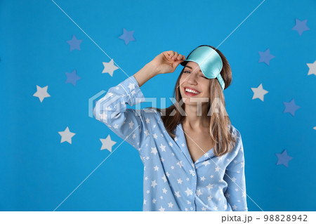 Beautiful woman wearing pajamas and sleep mask on light blue background. Bedtime Beautiful woman wearing pajamas and sleep mask on light blue background. Bedtime 98828942