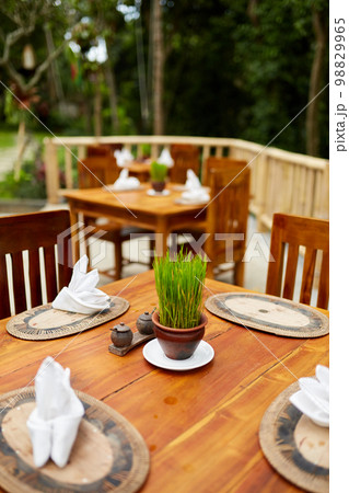 Live grass in a small pot decorating a wooden table outside in an eco restaurant. Live grass in a small pot decorating a wooden table outside in an eco restaurant. 98829965
