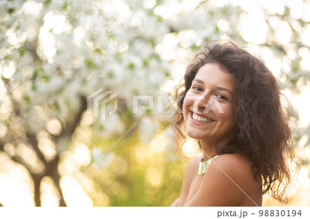 A young brunette girl poses with a blossoming cherry branch A young brunette girl poses with a blossoming cherry branch 98830194
