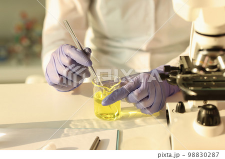 The scientist hands with a pipette in a yellow liquid The scientist hands with a pipette in a yellow liquid 98830287