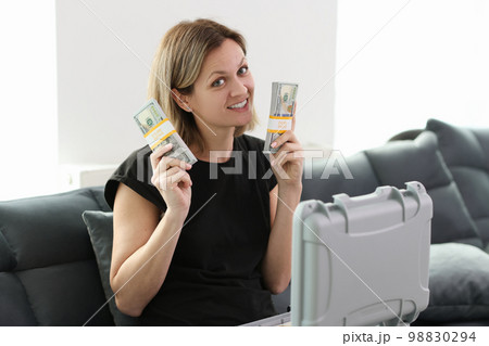 A woman sitting on the couch shows packs of money A woman sitting on the couch shows packs of money 98830294