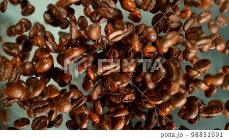 Freeze motion shot of rotating coffee beans, brown gradient background Freeze motion shot of rotating coffee beans, brown gradient background 98831691