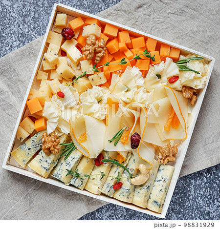 Assorted sorts of cheese on a wooden plate, grey background, top view 98831929
