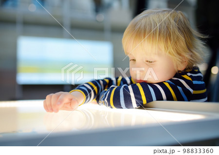 Little caucasian boy is looking an exposition in a scientific museum. Keen child is exploring of exhibits. Education and entertainment for children. Activities for family with kids. Little caucasian boy is looking an exposition in a scientific museum. Keen child is exploring of exhibits. Education and entertainment for children. Activities for family with kids. 98833360