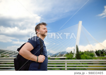 Portrait of middle age man on the background of cable stayed bridge. Millennium bridge is above Moraca river in Podgorica, Montenegro. 98833405
