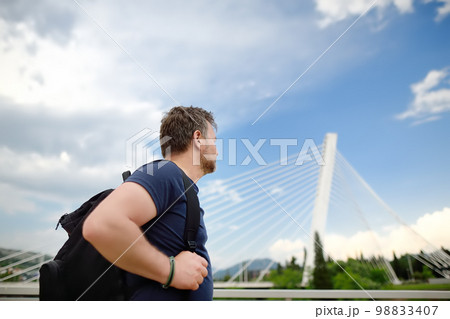 Portrait of middle age man on the background of cable stayed bridge. Millennium bridge is above Moraca river in Podgorica, Montenegro. 98833407
