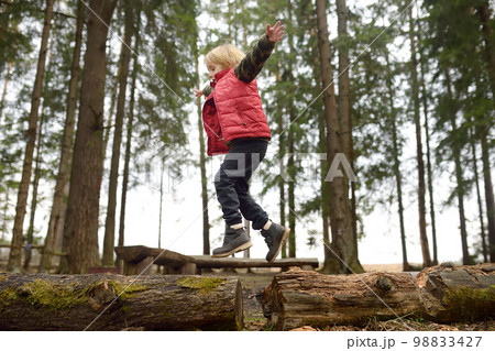 Little boy in red vest is playing branch and having fun in forest on early spring day. Activity for children. Outdoor recreation for family Little boy in red vest is playing branch and having fun in forest on early spring day. Activity for children. Outdoor recreation for family 98833427