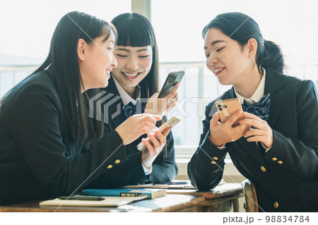 学校の教室でスマホを使う女子高生 学校の教室でスマホを使う女子高生 98834784