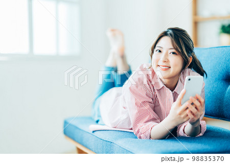 リビングでスマートフォンを操作する若い女性。 98835370