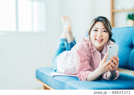 リビングでスマートフォンを操作する若い女性。 98835371