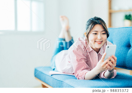 リビングでスマートフォンを操作する若い女性。 98835372