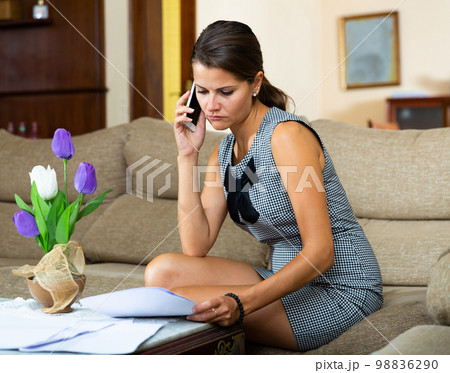 Girl filling out documents and talking on phone 98836290