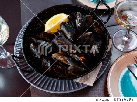 Steamed mussels in shells with lemon in metal serving pan Steamed mussels in shells with lemon in metal serving pan 98836295
