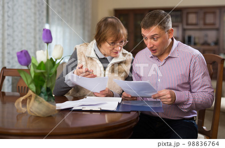 Man with elderly mother discussing documents Man with elderly mother discussing documents 98836764