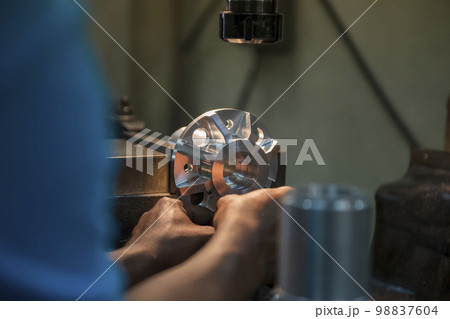 The machine operator setup the metal parts with NC milling machine. 98837604