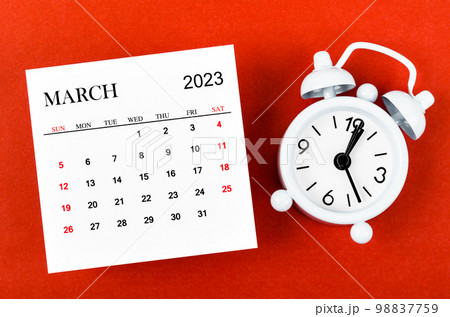 The March 2023 Monthly calendar year with alarm clock on red background. The March 2023 Monthly calendar year with alarm clock on red background. 98837759