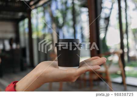 Presenting black cup of hot coffee in a cafe. 98838725