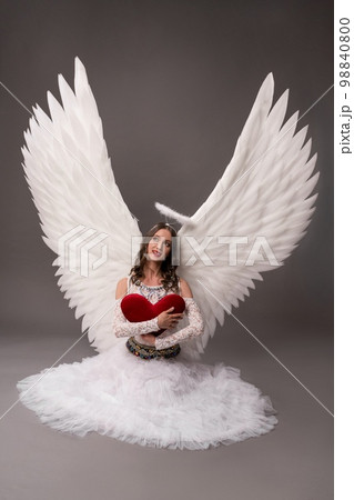 Woman in white dress with angel wings hold heart 98840800
