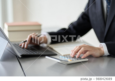 お金関係の資格の勉強をする男性の手元 98842689