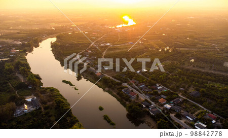 Aerial view of the Ping River across rice fields and rural villages during sunset. Views of Chiang Mai villages and the Ping River from a drone. Aerial view of the Ping River across rice fields and rural villages during sunset. Views of Chiang Mai villages and the Ping River from a drone. 98842778