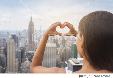 New York Tourist doing heart shape with hands gesture at NYC skyline view from rooftop. View from behind, USA Travel vacation destination 98842968