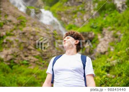 Looking up smiling 32 years old male man on nature mountain waterfall. Summer hiking, leisure activities in public park. European caucasian white young male. Waist up lifestyle portrait Looking up smiling 32 years old male man on nature mountain waterfall. Summer hiking, leisure activities in public park. European caucasian white young male. Waist up lifestyle portrait 98843440