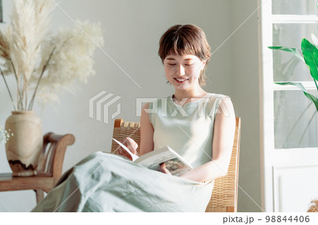 窓際でワンピース姿で読書をする若い女性 98844406