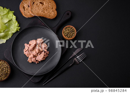 Delicious canned tuna meat on a black ceramic plate on a dark concrete background Delicious canned tuna meat on a black ceramic plate on a dark concrete background 98845284