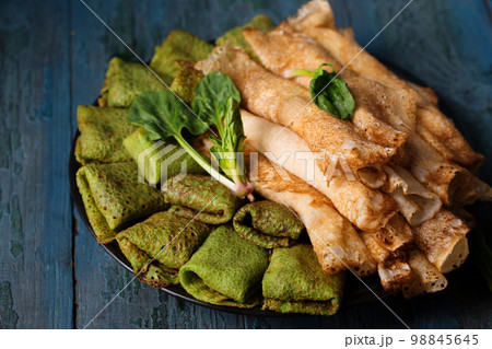 Pancakes with sweet and salty filling on a plate, decorated with spinach leaves Pancakes with sweet and salty filling on a plate, decorated with spinach leaves 98845645