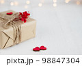 Valentine's Day gift box of craft paper with hearts and red flowers on the white wooden background. 98847304