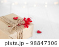Valentine's Day gift box of craft paper with hearts and red flowers on the white wooden background. 98847306