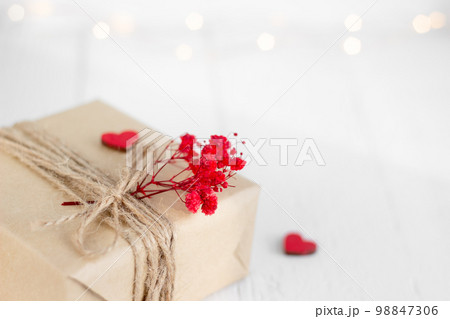 Valentine's Day gift box of craft paper with hearts and red flowers on the white wooden background. 98847306