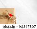 Gift box of craft paper with hearts on the white wooden background. Valentine's Day. 98847307