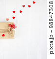 Valentine's Day flatlay. Gift box of craft paper with hearts and red flowers on the white wooden background. 98847308