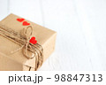Gift box of craft paper with hearts on the white wooden background. Valentine's Day. 98847313