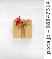 Gift box of craft paper with red flowers on the white wooden background. Valentine's Day. Happy birthday. 98847314