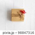 Gift box of craft paper with red flowers on the white wooden background. Valentine's Day. Happy birthday. 98847316